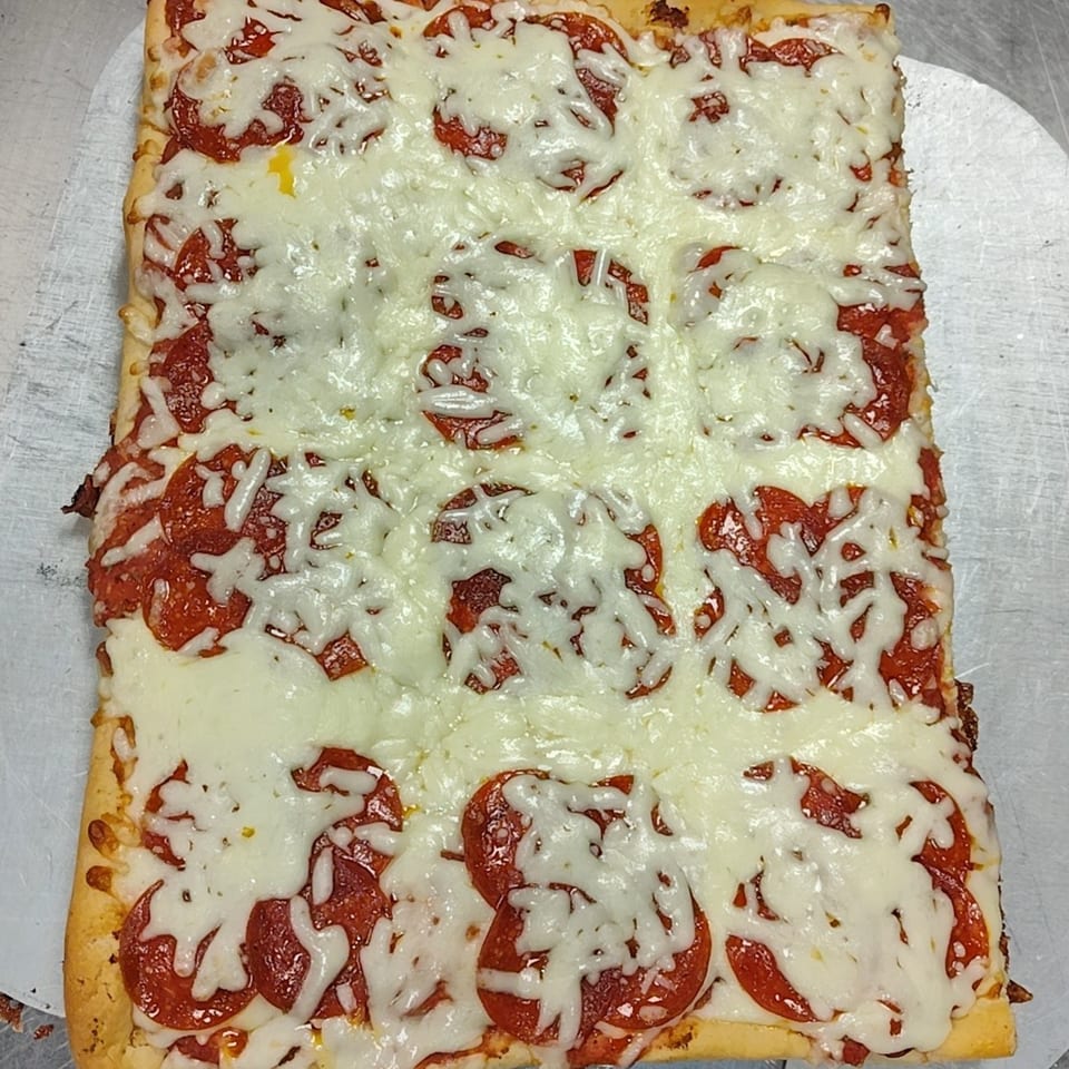 A rectangular Buzzi's Pizza with melted mozzarella cheese and pepperoni slices on a metal tray.
