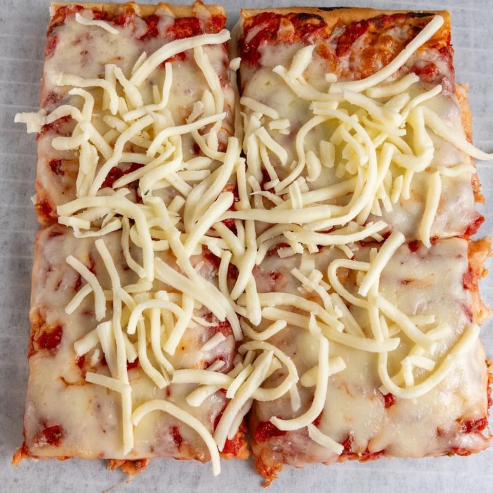 Four square slices of Buzzi's Pizza with melted cheese and tomato sauce.