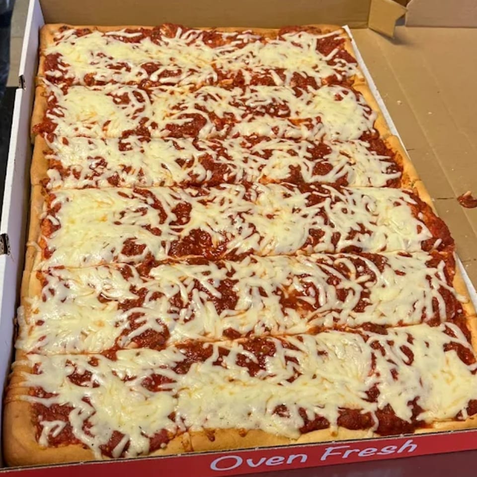 A large rectangular Buzzi's Pizza, cut into squares, with red sauce and melted white cheese.